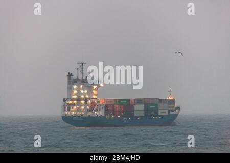 Myrtleville, Cork, Irlanda. 7 maggio 2020. Nave portacontainer Greetje ancorata al largo della costa in nebbia a Myrtleville, Co. Cork con un carico da Southampton nel Regno Unito. In tempi critici durante l'emergenza del Covid-19 l'economia irlandese dipende dalle importazioni che costituiscono un'ancora di salvezza per il paese. Mantenere aperta questa linea di approvvigionamento vitale è il porto di Cork, dove arriva la maggior parte delle importazioni dei paesi. - credito; David Creedon / Alamy Live News Foto Stock