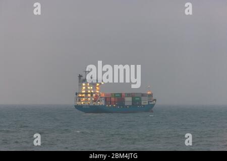 Myrtleville, Cork, Irlanda. 7 maggio 2020. Nave portacontainer Greetje ancorata al largo della costa in nebbia a Myrtleville, Co. Cork con un carico da Southampton nel Regno Unito. In tempi critici durante l'emergenza del Covid-19 l'economia irlandese dipende dalle importazioni che costituiscono un'ancora di salvezza per il paese. Mantenere aperta questa linea di approvvigionamento vitale è il porto di Cork, dove arriva la maggior parte delle importazioni dei paesi. - credito; David Creedon / Alamy Live News Foto Stock