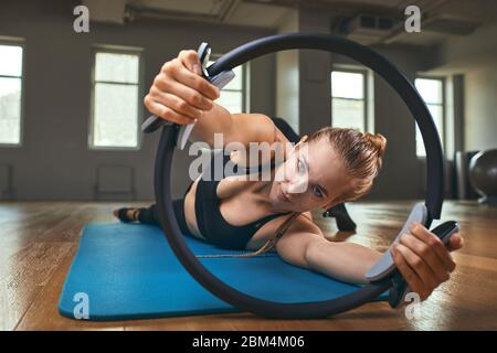 Giovane modello di fitness donna atleta in abbigliamento sportivo facendo allenamento stretching con espansore in gomma. Bodybuilding stile di vita sano concetto immagine Foto Stock