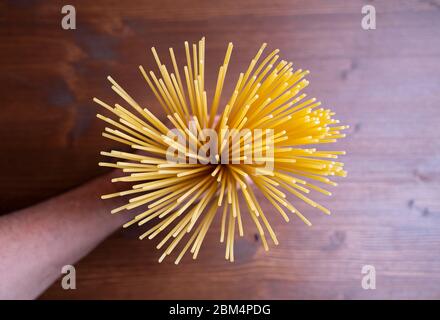 spaghetti crudi in mano su un tavolo di legno Foto Stock