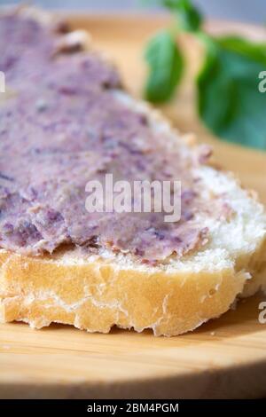 Pasta di pate di fagioli impaccata di proteine vegane spalmata su una fetta di pane Foto Stock