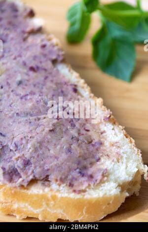 Pasta di pate di fagioli impaccata di proteine vegane spalmata su una fetta di pane Foto Stock