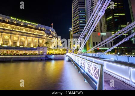 Singapore 30. Dicembre 2019 : Ponte Cavenagh di notte, sullo sfondo l'Hotel Fullerton Foto Stock