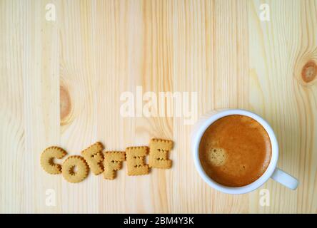 Vista dall'alto di una tazza di caffè caldo isolato su un tavolo di legno con biscotti a forma di alfabeto e spazio libero Foto Stock