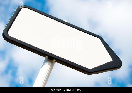 Vista ad angolo basso di un bianco, bianco, che punta il senso, posto di segnale di informazioni contro un cielo blu con le nuvole. Foto Stock