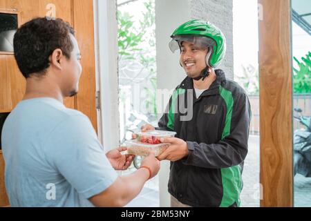 Uomo di consegna che consegna il cibo ad un uomo a casa - concetto di servizio di shopping del cibo in linea Foto Stock