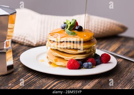 Sciroppo d'acero che versa su una pila di mini pancake. Foto Stock