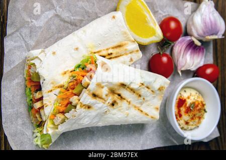 Shawarma fatto in casa, burrito, involtino di pollo con verdure e salsa. Vista dall'alto ingredienti, primo piano Foto Stock
