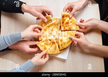 Mani che prendono le fette di tortilla con formaggio di cottage o vertuta da un piatto di legno, primo piano Foto Stock