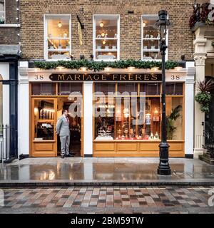 Mariage Freres, Covent Garden, Londra. Un acquirente di vendita dal look elegante che si trova all'ingresso di un esclusivo negozio di tè. Foto Stock