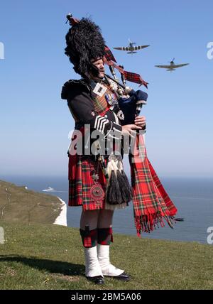 EMBARGOED A 0001 VENERDÌ 08 MAGGIO tubo maggiore Andy Reid delle Guardie scozzesi gioca le sue pipe sulle scogliere di dover, Kent, come due Spitfire dalla Battaglia di Gran Bretagna Memorial volo aereo, in anticipo rispetto alle commemorazioni per celebrare il 75 ° anniversario di VE Day. Foto Stock