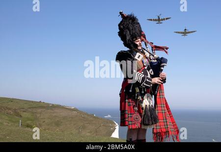 EMBARGOED A 0001 VENERDÌ 08 MAGGIO tubo maggiore Andy Reid delle Guardie scozzesi gioca le sue pipe sulle scogliere di dover, Kent, come due Spitfire dalla Battaglia di Gran Bretagna Memorial volo aereo, in anticipo rispetto alle commemorazioni per celebrare il 75 ° anniversario di VE Day. Foto Stock