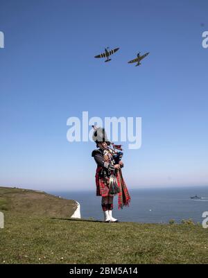 EMBARGOED A 0001 VENERDÌ 08 MAGGIO tubo maggiore Andy Reid delle Guardie scozzesi gioca le sue pipe sulle scogliere di dover, Kent, come due Spitfire dalla Battaglia di Gran Bretagna Memorial volo aereo, in anticipo rispetto alle commemorazioni per celebrare il 75 ° anniversario di VE Day. Foto Stock