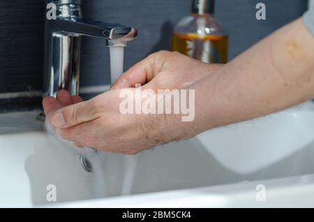 L'uomo sta lavando la mano con sapone, per proteggere dalla pandemia del coronavirus Foto Stock