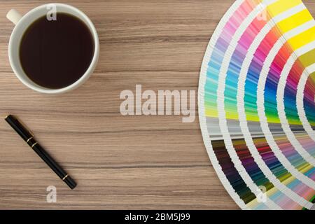 Gamma di carte colore su scrivania in legno con caffè e penna Foto Stock