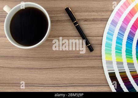 Gamma di carte colore su scrivania in legno con caffè e penna Foto Stock