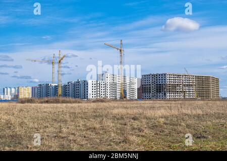 Panorama di edifici residenziali a più piani e multiappartamenti in costruzione su un campo agricolo abbandonato Foto Stock