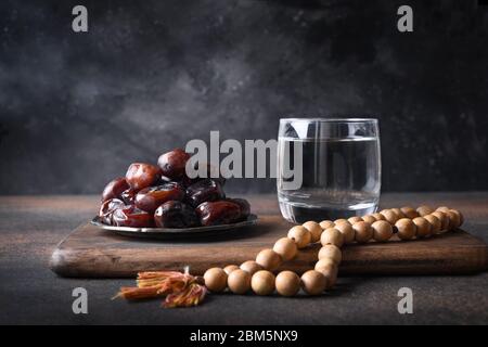 Ramadan. Perline di preghiera in legno e datteri in ciotola su marrone. EID Mubarak. Tradizione religiosa. Foto Stock