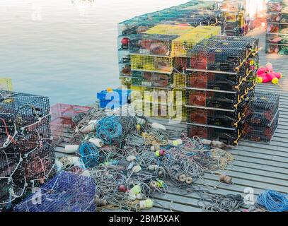 Molte trappole di aragosta impilate su un molo con corda e bouys pronti per essere messi al lavoro. Foto Stock