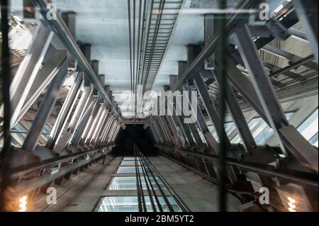 Interno dell'asta dell'ascensore, vista dall'ascensore che mostra cavi a fune e supporti in acciaio con sfocatura del movimento Foto Stock