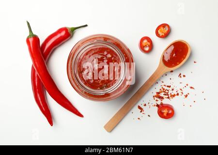 Composizione con peperoncino, spezie e salsa su fondo bianco Foto Stock