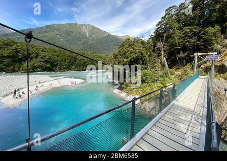 Limpide piscine blu turchesi e ponte sospeso sul fiume Makarora nel Parco Nazionale del Monte Aspiring, Nuova Zelanda Foto Stock