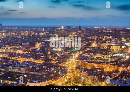 L'Aia, Paesi Bassi paesaggio urbano con Grote di Sint-Jacobskerk torre in lontananza al tramonto. Foto Stock