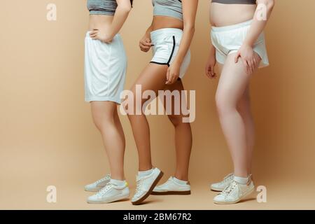 Vista tagliata di donne sportive multiculturali in shorts su beige Foto Stock