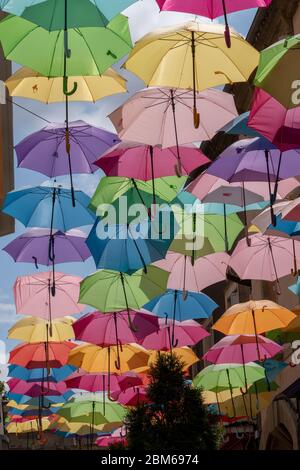 Decorazione di strada con ombrelloni colorati appesi tra gli edifici sul vicolo Foto Stock