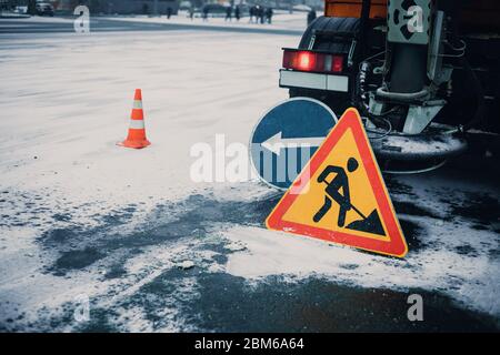 Spazzaneve sgombro da neve e ghiaccio.spazzaneve rimuovere la neve dalla strada della città.segnale stradale di avvertimento e cono arancione.Servizio invernale ve Foto Stock