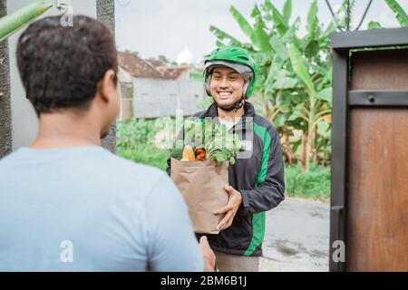 corriere maschile asiatico che consegna la drogheria al cliente. cibo consegna online Foto Stock