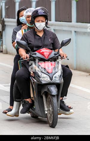 Tre ragazze con maschera di fronte in moto durante la pandemia Covid 19, Bangkok, Thailandia Foto Stock