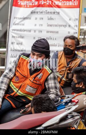 Motociclista con maschera facciale in attesa di clienti durante Covid 19 pandemic, Bangkok, Thailandia Foto Stock
