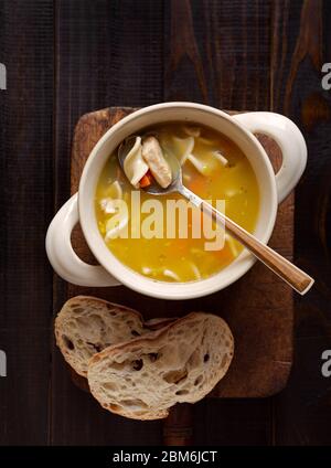 Vista dall'alto della zuppa di spaghetti di pollo con pane su una superficie di legno Foto Stock