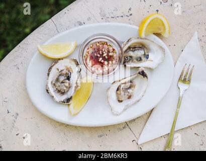 Ostriche con salsa di mignonette e limone Foto Stock