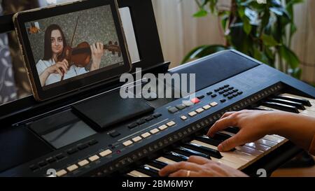 Violinista e pianista giocano insieme su Internet, essendo isolatamente per la pandemia del coronavirus Foto Stock