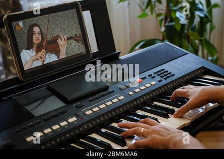 I musicisti provano online a causa della pandemia di coronavirus. Violinista e pianista giocano insieme su Internet, essendo in isolamento Foto Stock