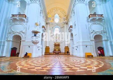 SALISBURGO, AUSTRIA - 1 MARZO 2019: Interno della Collegiata con pavimento in pietra a mosaico, pareti bianche scolpite e altare in legno sullo sfondo, Foto Stock