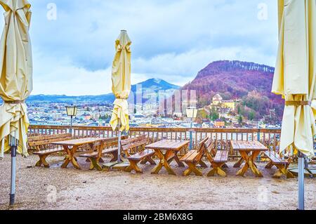 L'accogliente terrazza con tavoli in legno e panche sulla cima del colle Monchsberg, con vista sulla vecchia Salisburgo, Austria Foto Stock