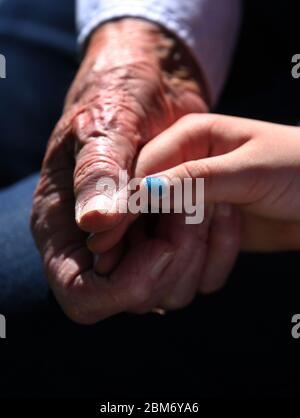 Zellingen, Germania. 7 maggio 2020. Una donna di 90 anni tiene la mano della sua bisnonna di sette anni durante una visita ad un parente. A causa delle misure allentate intorno al coronavirus, è possibile visitare nuovamente il circolo più vicino della famiglia in Baviera. Credit: Karl-Josef Hildenbrand/dpa/Alamy Live News Foto Stock