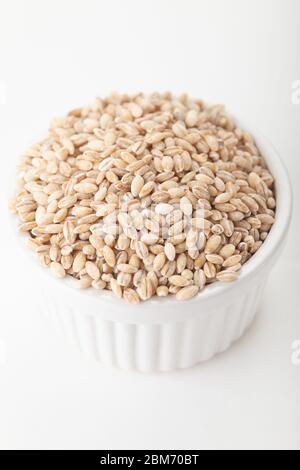 Grani di orzo perlato in un piatto di ramekin bianco Foto Stock