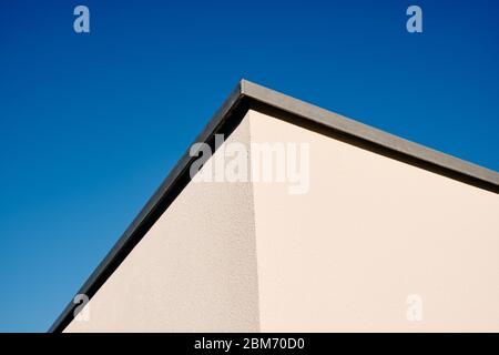 Un'architettura astratta di due pareti e un angolo di una casa moderna con intonaco bianco contro il cielo azzurro. Visto in Germania nel mese di marzo. Foto Stock