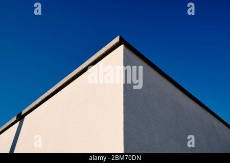 Un'architettura astratta di due pareti e un angolo di una casa moderna con intonaco bianco contro il cielo azzurro. Visto in Germania nel mese di marzo. Foto Stock