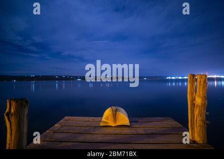 Libro aperto in un porto di mare di notte con una luce notturna. Concetto: Lettura  notturna leasure in spiaggia Foto stock - Alamy