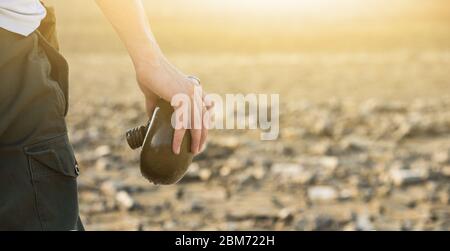 Uomo con fiasca nel deserto. Siccità e scarsità di acqua causate dal riscaldamento globale Foto Stock