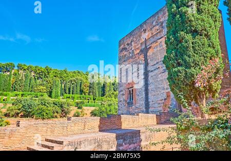 Esplora la fortezza conservata dell'Alhambra con pareti in mattoni, la Torre de la Cautiva (Torre del Captive) e i giardini Generalife sullo sfondo, Granada, SPAI Foto Stock