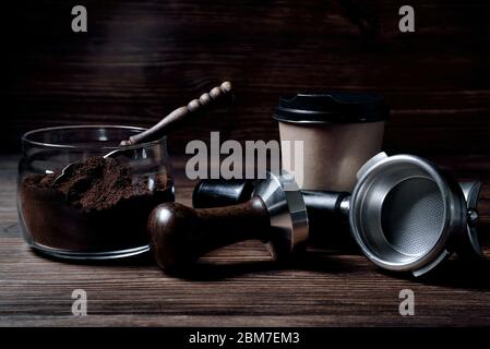 vasetto di vetro con toviglietto di carta da caffè macinato con cucchiaio di legno su sfondo marrone naturale di legno Foto Stock