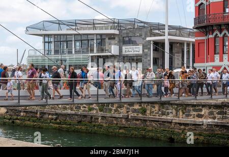 Città del Capo, Sudafrica. 2019. I visitatori del V&A Waterfront attraversano il ponte sospeso sull'ingresso sul lungomare di Città del Capo. Foto Stock