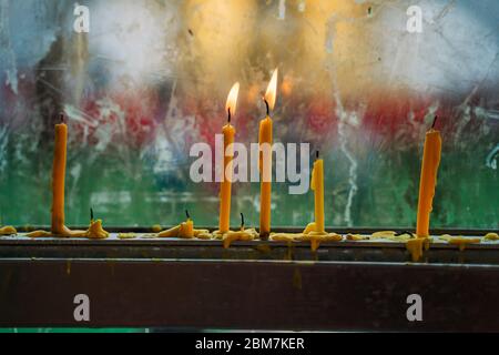 Candele illuminate nel tempio buddista in Thailandia mostrando rispetto Foto Stock