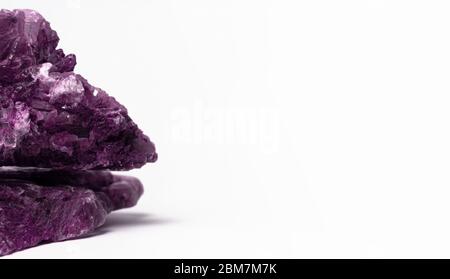 Due pezzi di gemma naturale viola sullo sfondo chiaro. Modello o mockup per banner, merci, cosmetici naturali o gioielli. Foto Stock